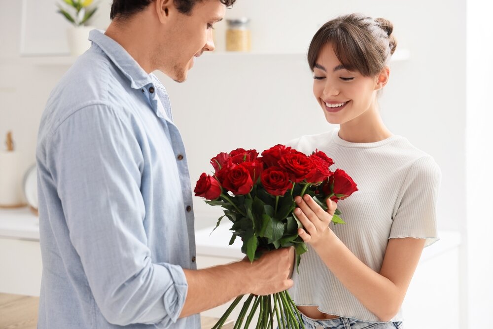 男性が女性にバラの花束を渡している画像