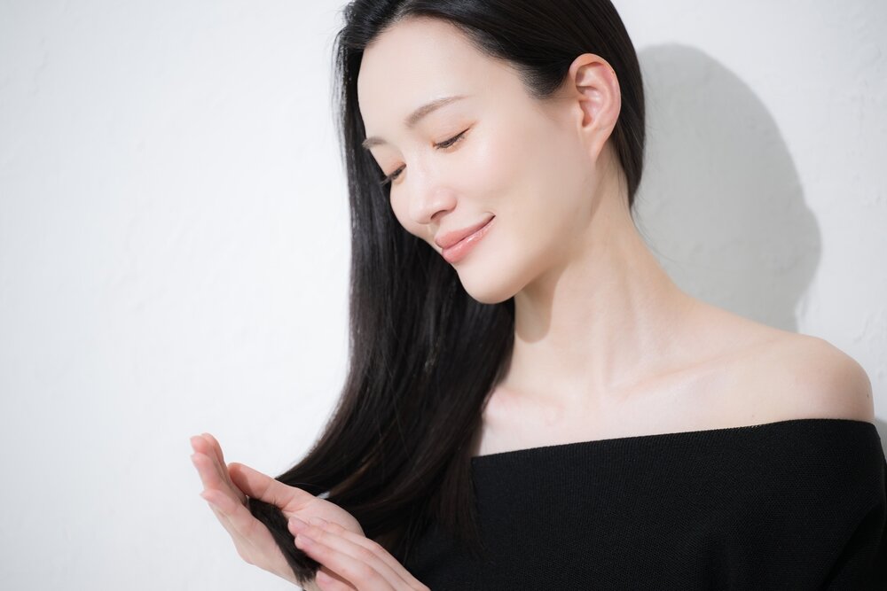 髪の長い女性が自分の髪の毛を触っている写真