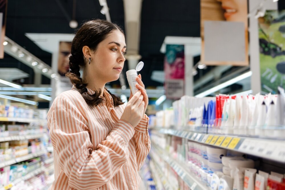 ボトルがたくさん売っている場所で香りを試している女性の写真