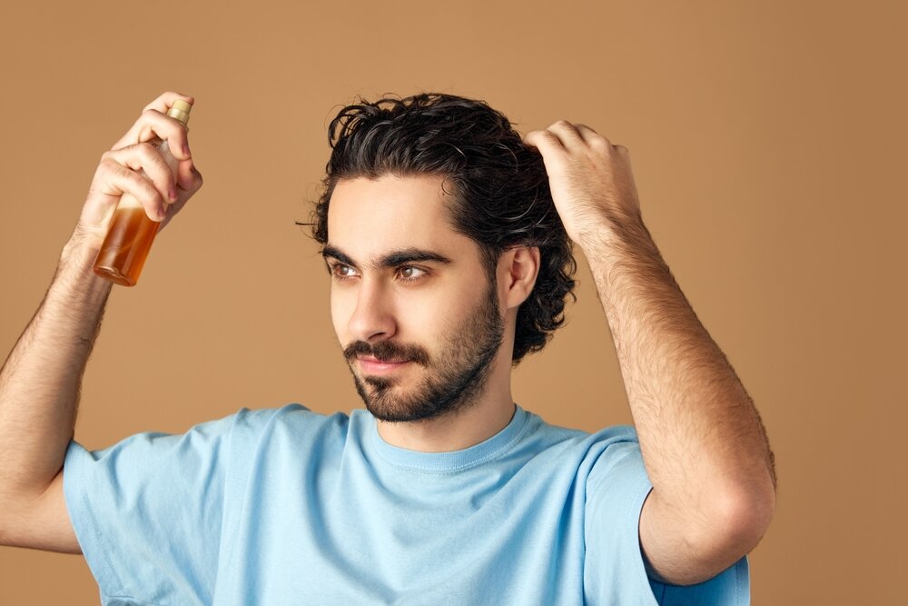 男性が頭にヘアミストをかけようとしている写真