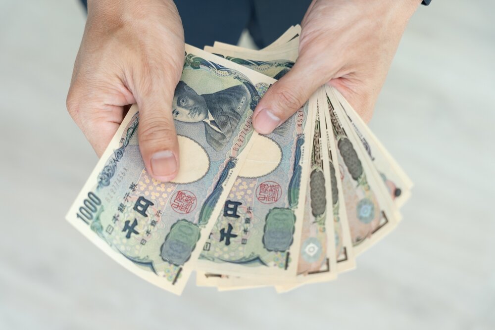 両手で千円札と一万円札を何枚か持っている人の写真