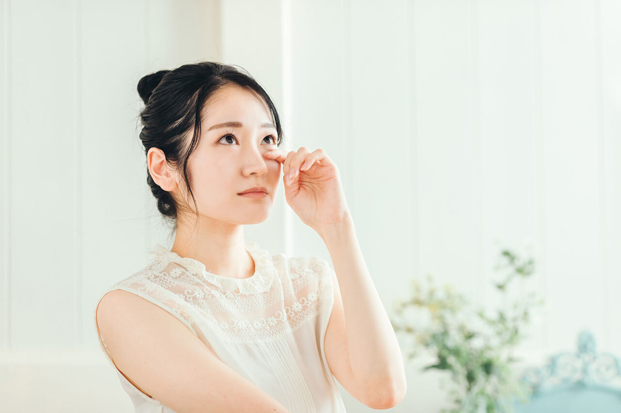 目の不調を感じて目元に指を添える女性